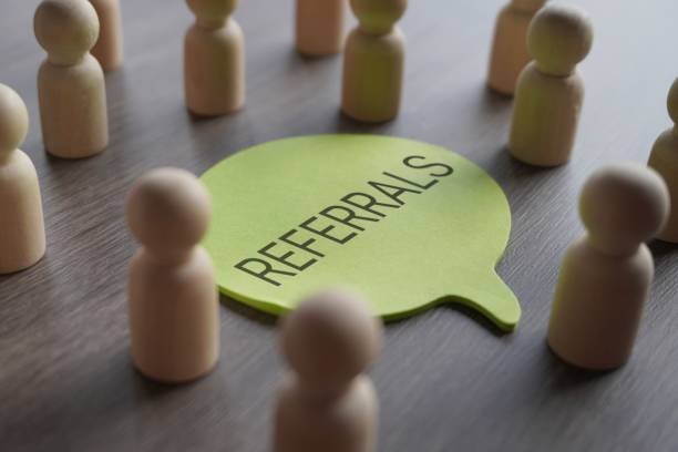 A group of wooden figurines surrounding a speech bubble with text REFERRALS. Recommendation, marketing, customer retention and loyalty concept